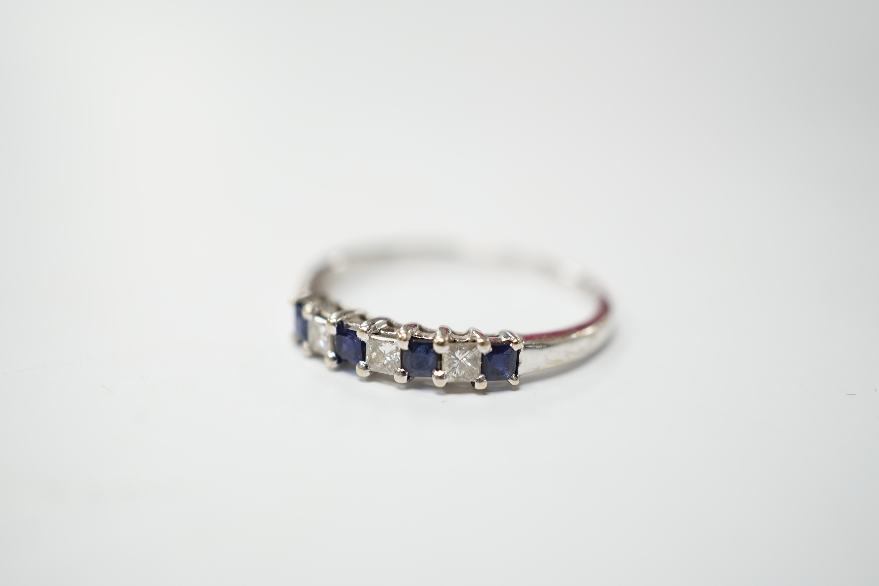 A modern 18k and plat, sapphire and diamond set seven stone half hoop ring, size O, gross weight 1.8 grams.